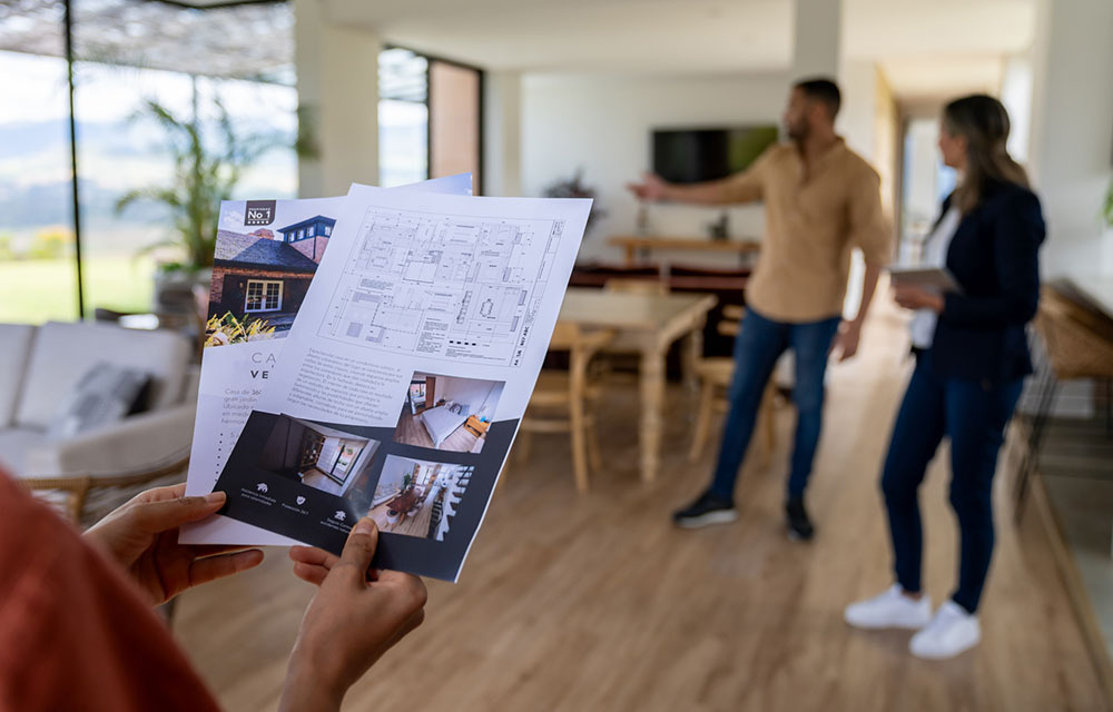 Close-up on a client looking at a house brochure at a real estate showing.