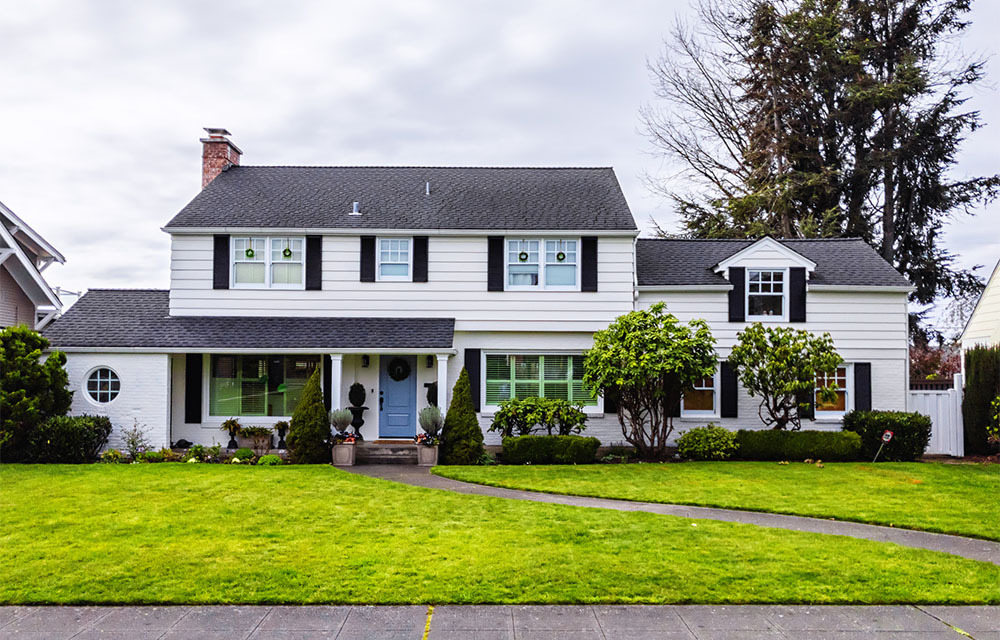 White suburban home with a healthy front yard on an overcast day.