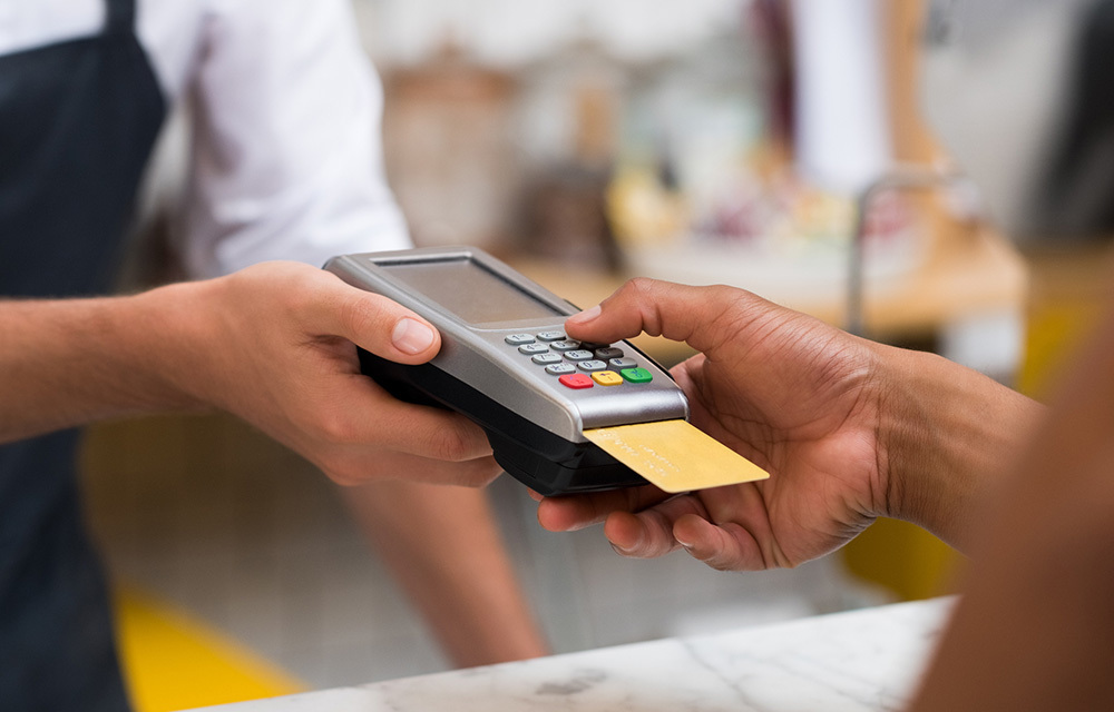 Close up of a person's hand swiping a credit card.