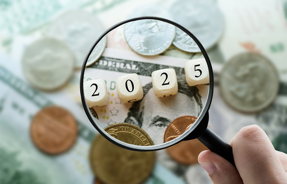 Magnifying glass focusing on a set of dice that spell out 2025 and are laying on cash.
