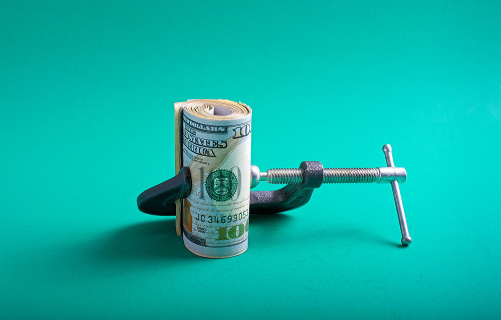 Rolled up cash being held with a tightened clamp.