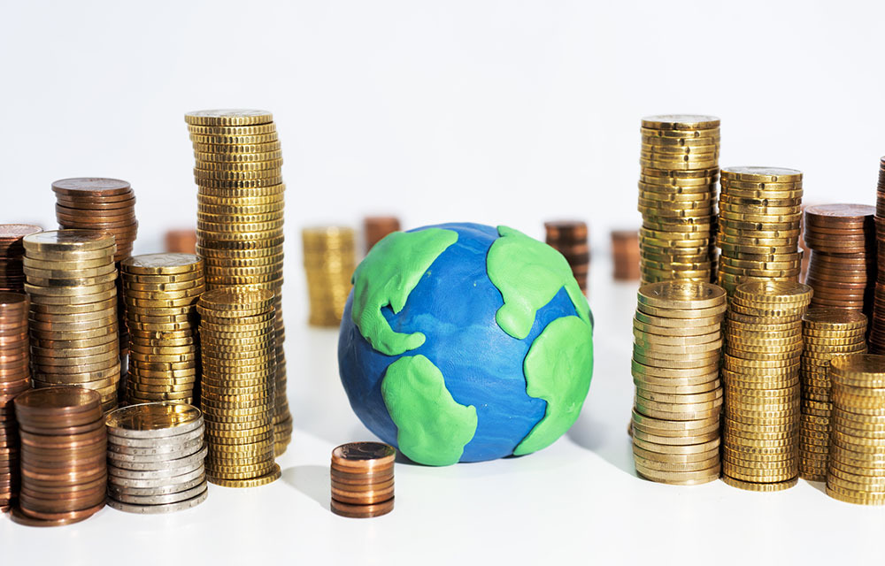 A clay model of Earth surrounded by stacks of coins on a white table.