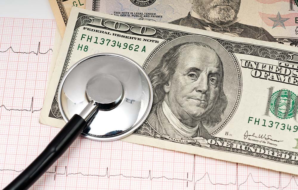 Hundred-dollar bill with a stethoscope laying on top.