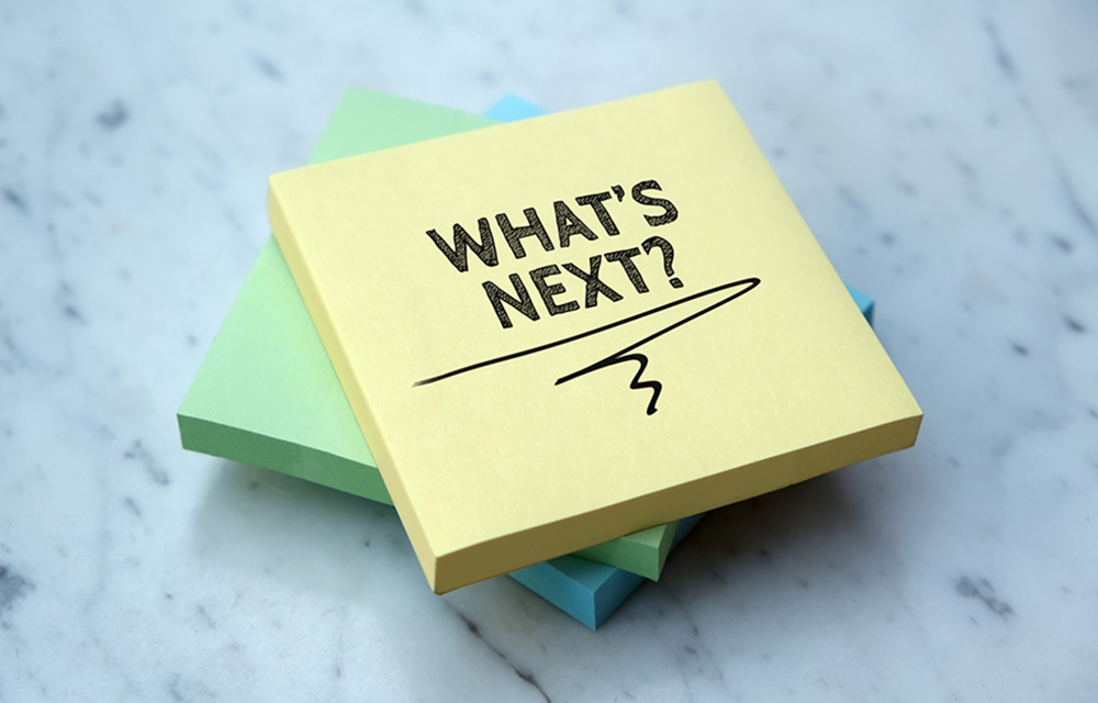 Three sticky note pads laying on top of each other with the two words what's next written on top.