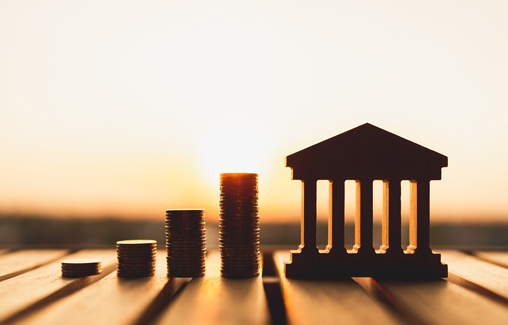 Silhouette of a bank building replica and stacks of change.