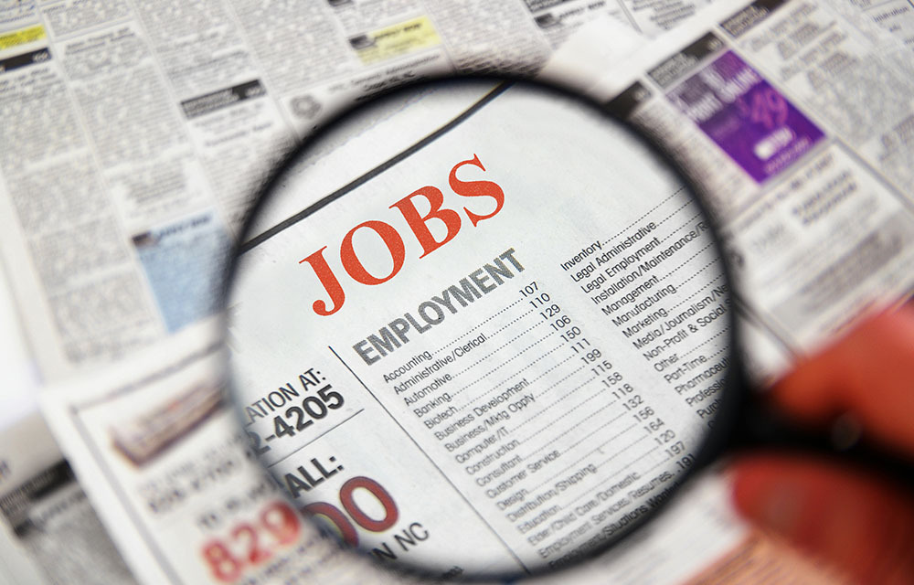 Magnifying glass over the jobs section of a newspaper.