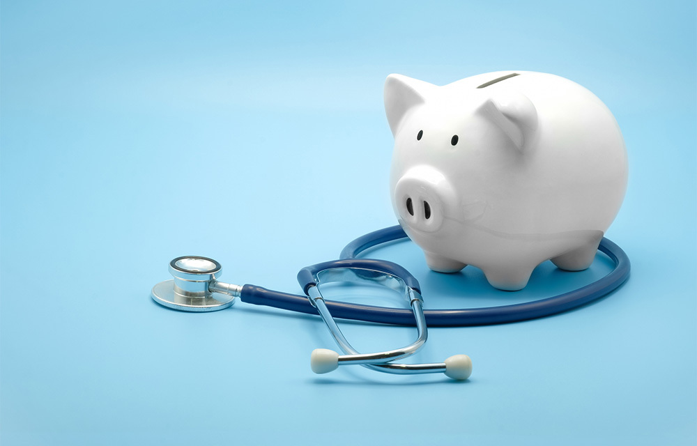 A piggy bank with a stethoscope laying around its feet.
