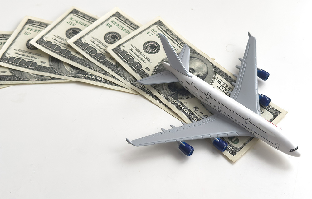 Toy plane and money on white background.