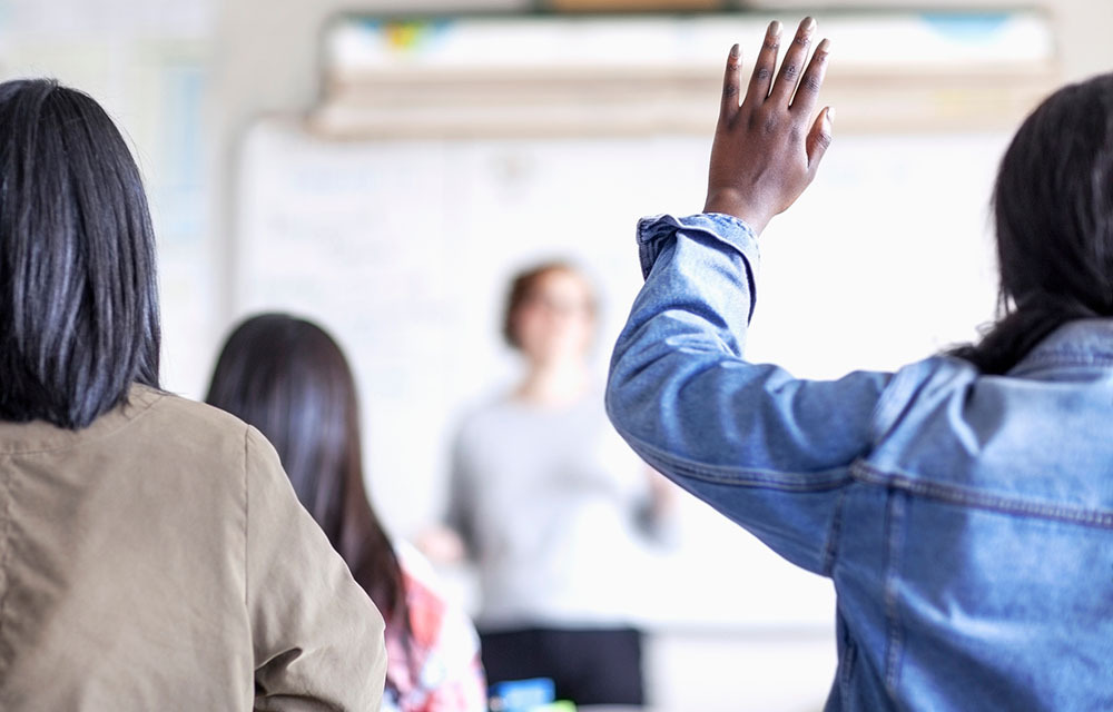 Student raises hand in classroom