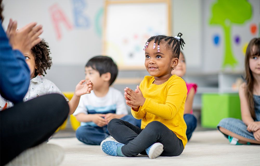 A teacher leads a sing-along with a group of happy preschoolers.