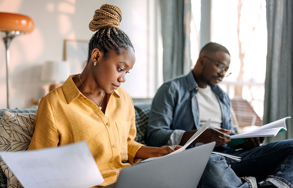 Couple sitting on their couch and reviewing paperwork together.