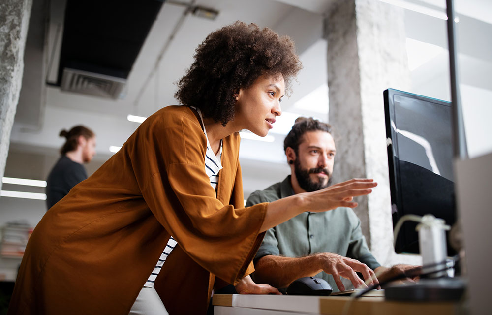 A woman discussing something with a male co-worker on his computer screen