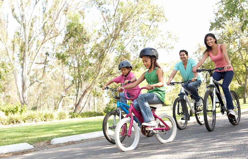 A family wearing helmets and riding bikes outside.