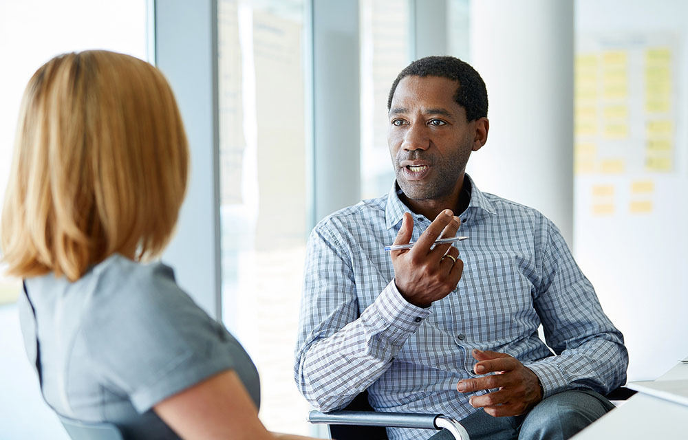 A man and woman talking while seated in an office.