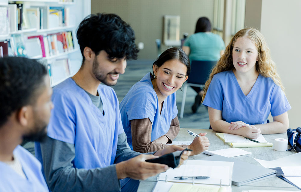 Group of medical students in blue scrubs studying together.