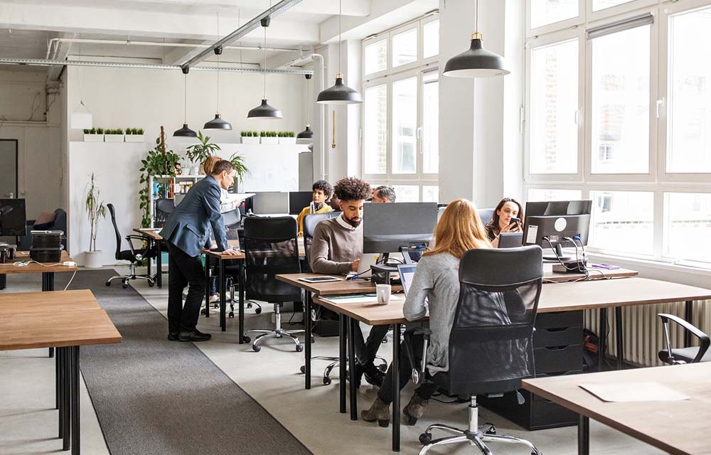 Modern office space with employees working at their computers and collaborating.