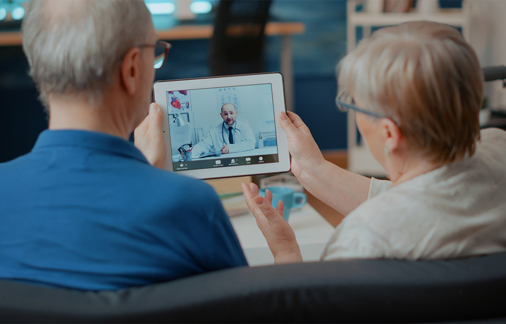 Senior couple attending online meeting with doctor on digital tablet, doing remote consultation at home.