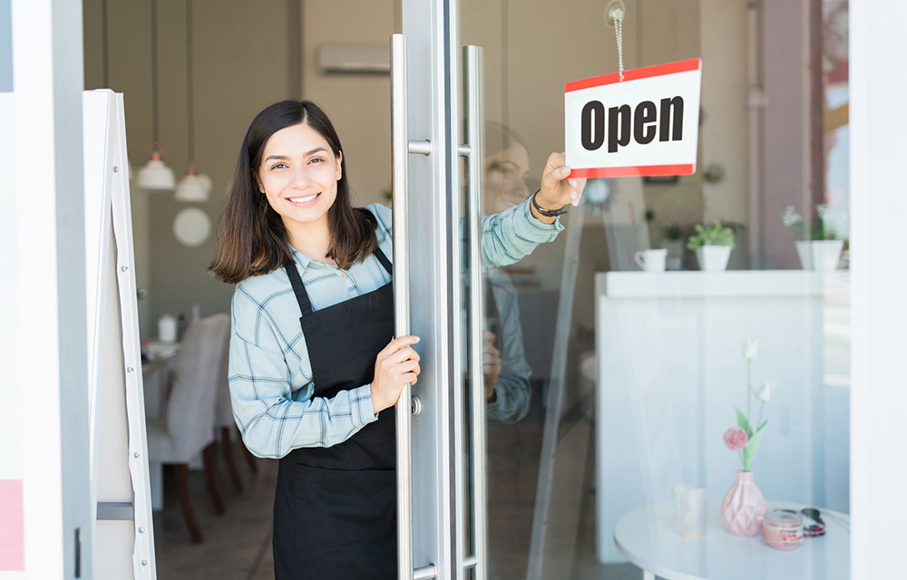 Woman business owner with "Open" shop sign