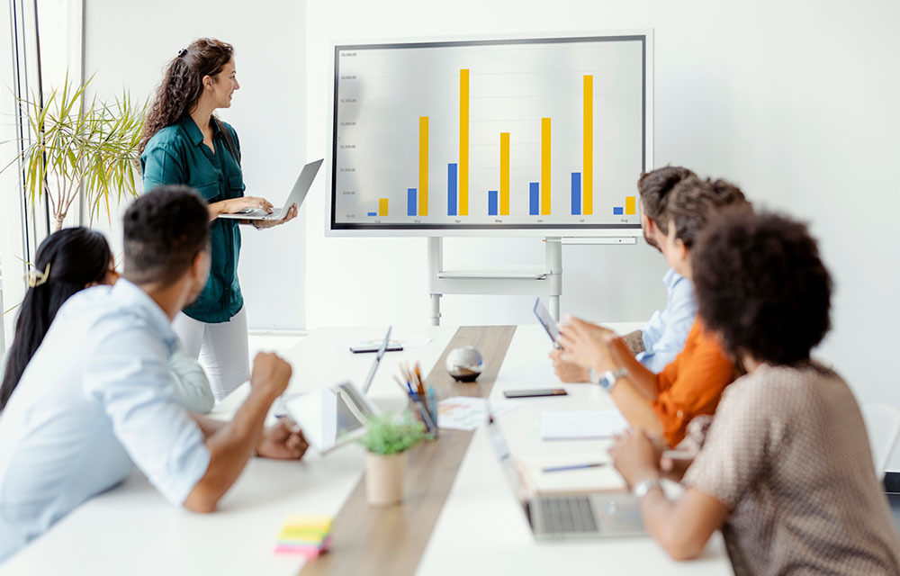 Woman presenting a chart on a screen to colleagues in a meeting