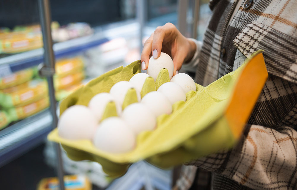 Close-up on the hands of a woman picking eggs in a supermarket