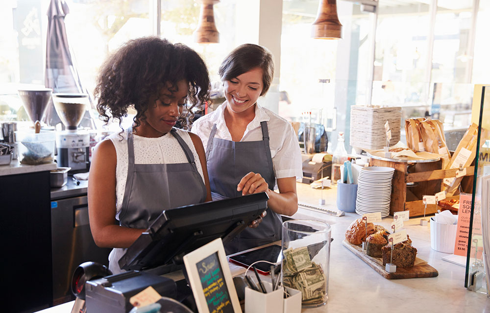 Two women working at a cash register in a cafe