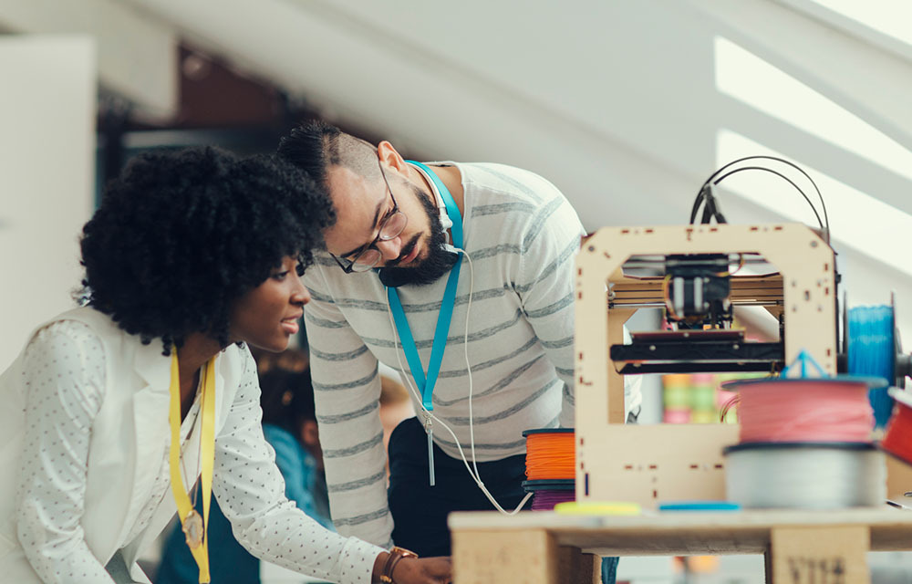 Two people working with a 3D printer