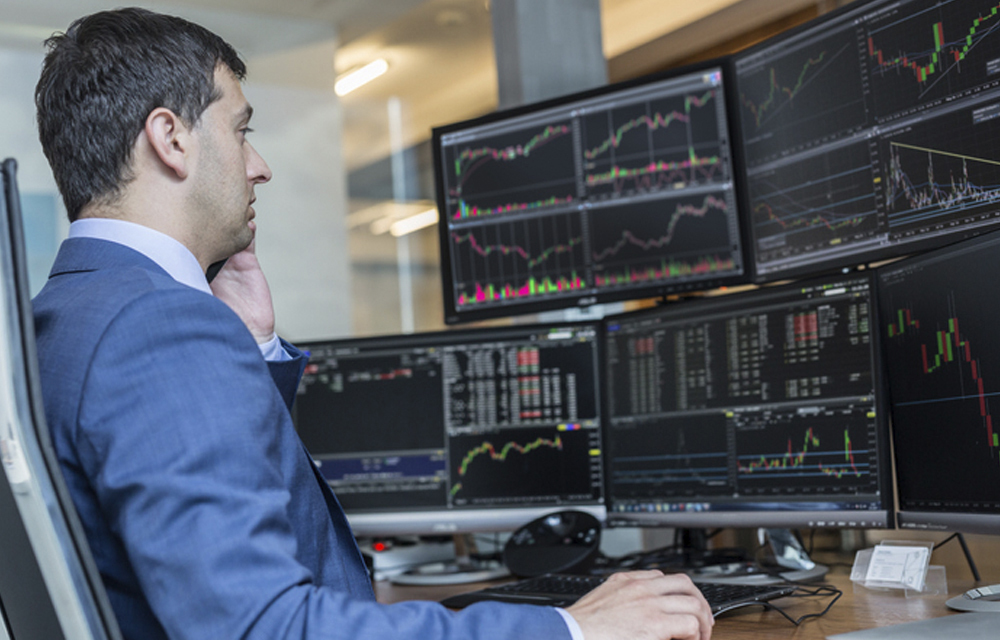 Man before a slew of monitors reviewing data