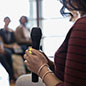 woman holding a microphone in front of a group of people