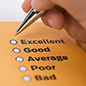 A person holding a pen, filling out a rating sheet ranging from Excellent to Bad