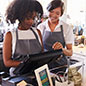 Two women working at a cash register in a cafe