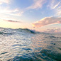 Ocean wave at sunrise in a tropical sea with reflections of the sky