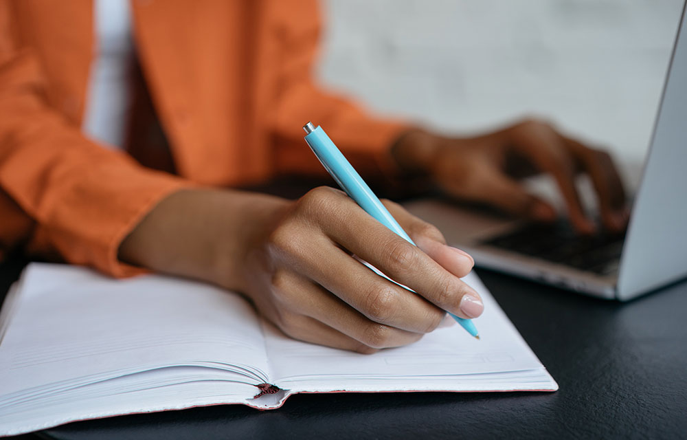 hands taking notes while online